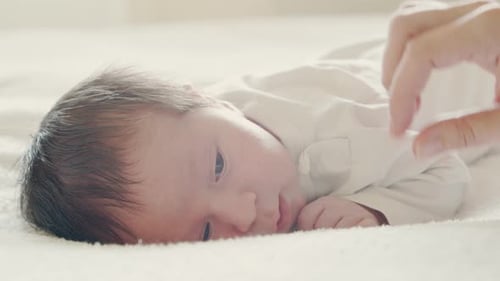 Newborn Infant Lying on Blanket, Hand Strokes Back