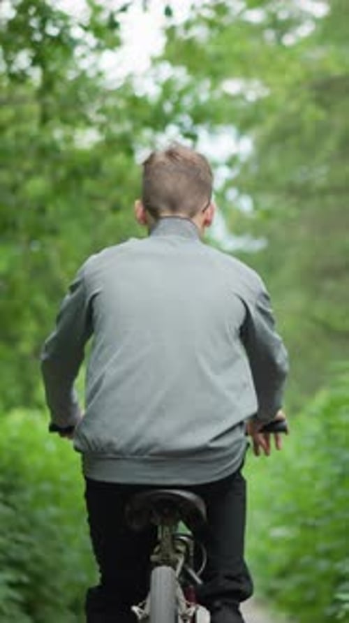 Young Boy Riding Bicycle Through Scenic Green Tunnel Surrounded By Lush Foliage