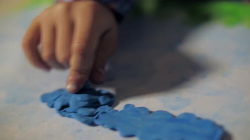 Child Hand Flattening Blue Clay Close Up