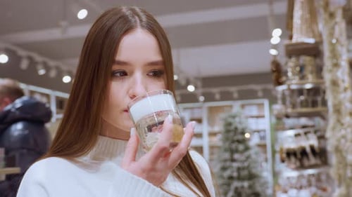 Lady Smelling Perfume in Mall Store with Other Shoppers in Background