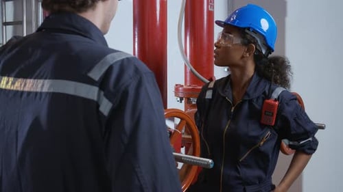 Young woman and man engineer check and examining pipeline and discussion in the factory.
