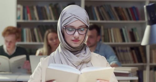 Close Up of Young Arab Muslim Woman in Hijab and Glasses Reading Book in Library Arabian Beautiful