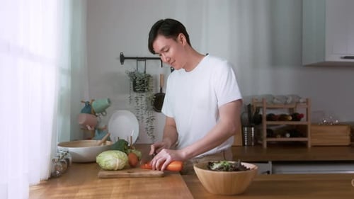 Young Adult Chopping Vegetables in Bright Kitchen