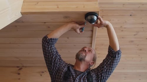 Man Installs Security Camera in Wood Paneled Home