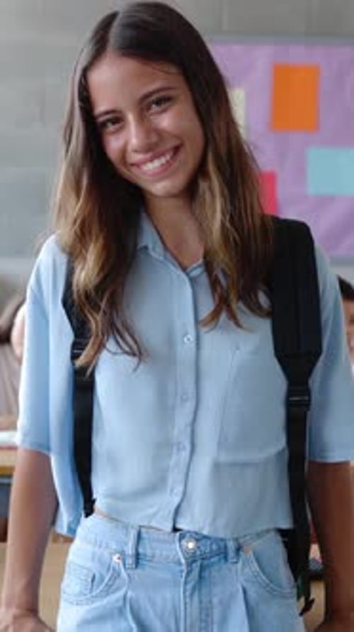Smiling Primary School Student Girl with Backpack Standing at Classroom
