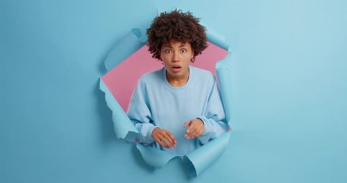 Shocked Woman Peeking Through Torn Paper