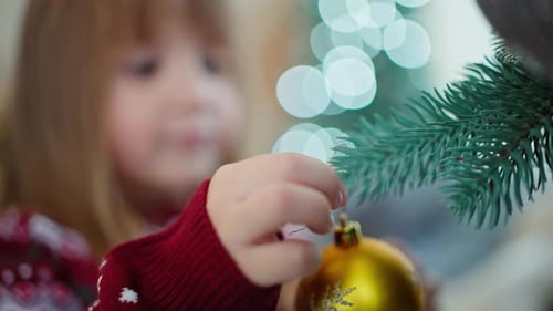 Child Decorating Christmas Tree with Ornament at Home
