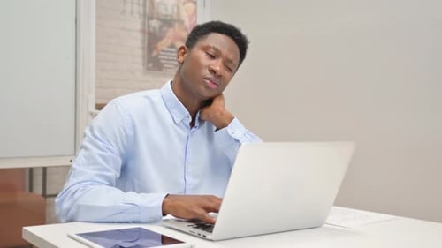 Man Working on Laptop in Office Looking Weary