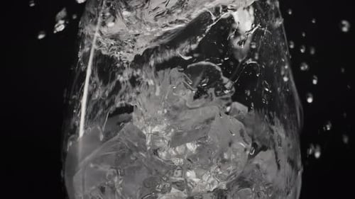 Water pouring onto ice cubes inside a clear glass