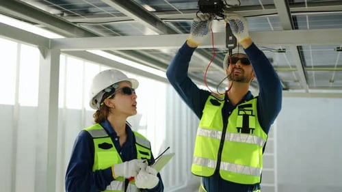 Professionelle Solartechniker inspizieren Paneele mit einem Multimeter und einem Tablet. Nachhaltige Energie