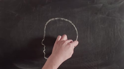 Word Idea is Written in Chalk on Chalkboard Above a Picture of a Man's Head with Colored Drawn