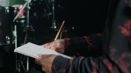 Black Man Holding Papers with Sheet Music and Asking Bandmate about It