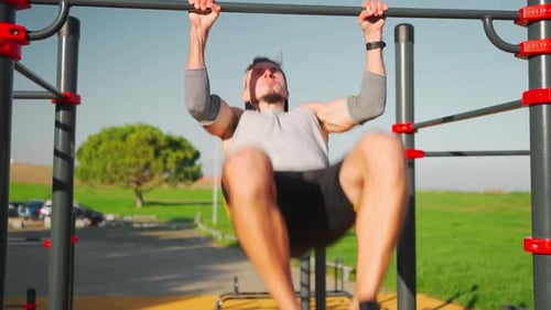 Athlete Man Does Pull Ups on Horizontal Bar Outdoors