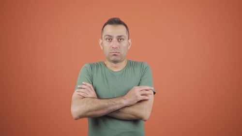Man with arms crossed pouting against orange background
