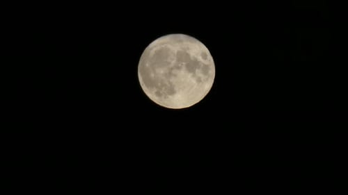 Full harvest moon lunar crater surface closeup passing across dark sky