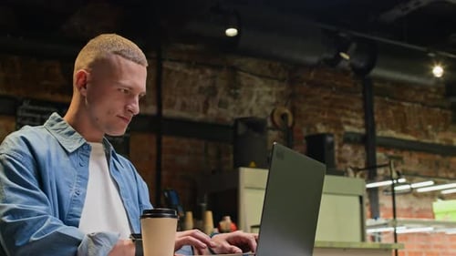 Jeune travailleur indépendant travaillant dans un ordinateur portable dans un café vide