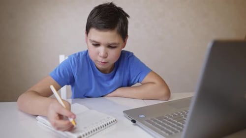 Child Studying With Laptop and Notebook at Home