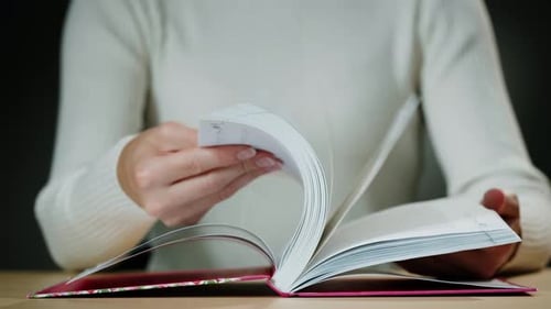 Woman Flicks Through Pages of Book Close Up