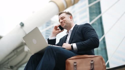 Smiling Man Working Outside Office Building on Phone