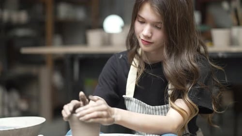 Young women is making earthenware at workshop.