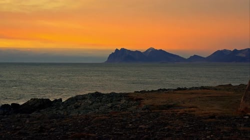 Rocky Seashore And Mountains On The Horizon At Sunset