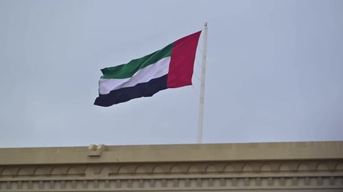 The UAE flag waves gracefully in the air in a close-up shot.