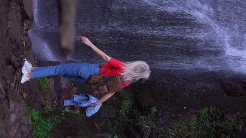 Back view of young woman standing in front of waterfall.