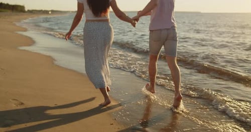 Young Loving Couple Have Fun Running on the Beach at Sunset