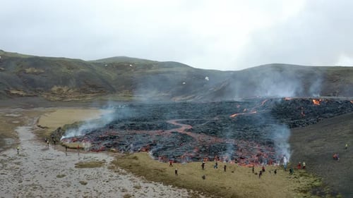 Aerial view over people near hot magma, volcano eruption scenery, in Iceland - rising, pull back, dr