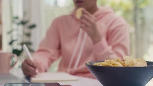 Girl Studies with Chips and Headphones at Home