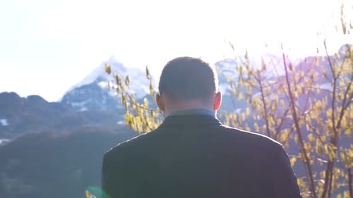 Man Filming Lake with Mountain View