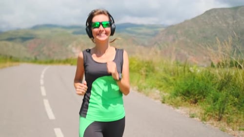 Athlete Runs on a Sunny Road with Hills and Mountains Ahead