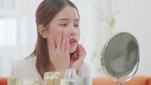 Woman Applying Makeup in the Mirror at Home