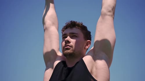 portrait of a young sweaty sportsman doing horizontal bar swings arms and shoulders push-ups