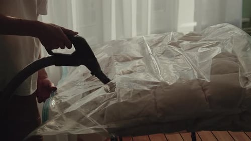 Person Vacuuming Air from a Storage Bag Indoors