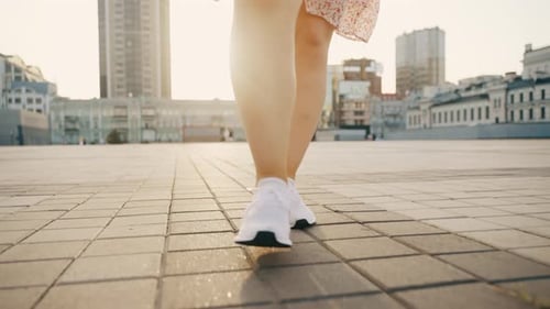 View of Female Legs in White Sneakers Walking Towards the Camera
