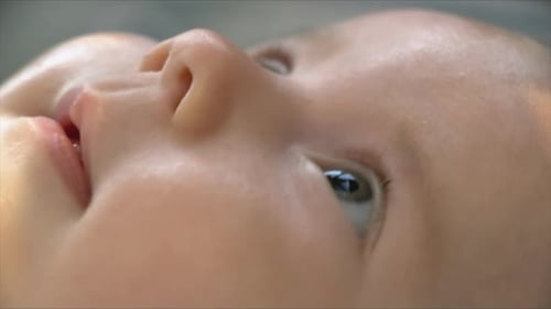 Shot of a baby her face. Looking up at her toys. CLOSE UP