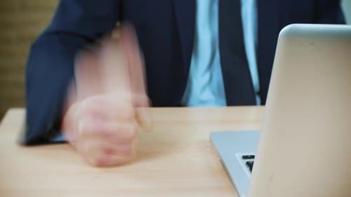 Adult Clenching Fist at Desk Next to Computer