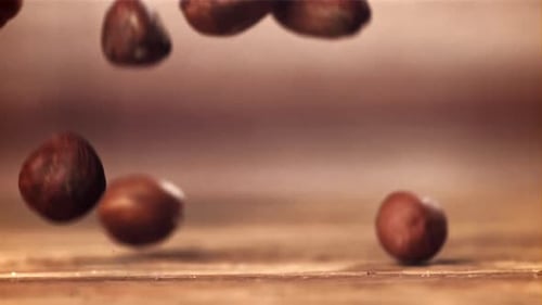 Hazelnuts Slowly Falling on Wooden Surface Close Up