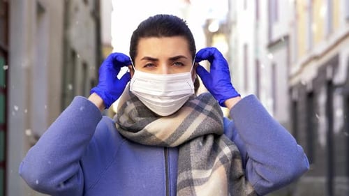 Woman Putting on Face Mask in Urban Setting