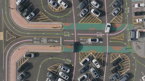 Looking down on a parking lot full of cars with green and pink guidelines from above.