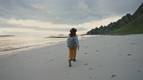 A Traveler in a Sweater Walks Along the North Sea Beach Enjoying the Waves