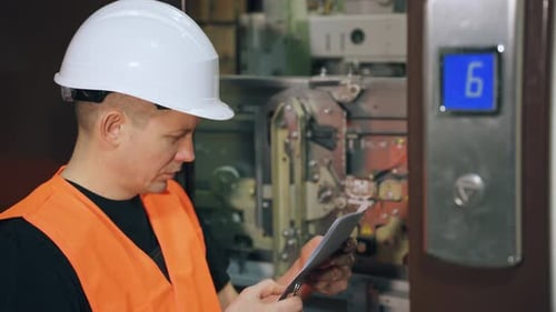 Installation of an Elevator Cabin in a Residential Complex A Male Utility Worker Adjusts the Lift