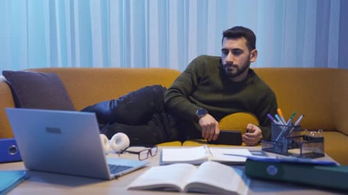 Young Adult Reclining on Couch Using Smartphone