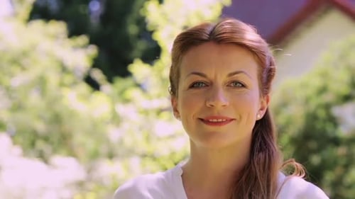 Happy smiling redhead woman enjoying summer outdoors in her garden