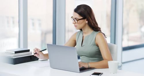 4k video footage of an attractive young businesswoman writing notes while working in her office