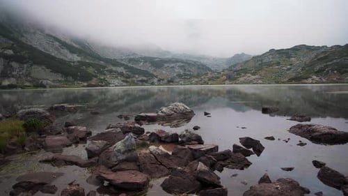 O lago de peixes em Rila Mountain, Bulgária. Laboratórios de tempo com uma névoa mística sobre o lago.