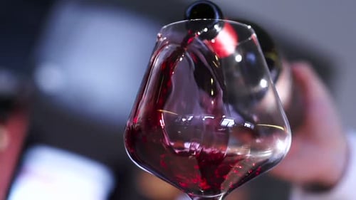 Mann gießt Rotwein wie Sauvignon in einer klassischen Weinglas-Zeitlupe ein