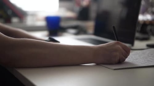 Person writing on paper in office setting