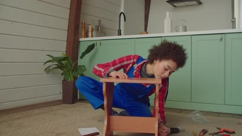 Une bricoleuse afro-américaine positive termine l'assemblage de meubles de bricolage d'intérieur